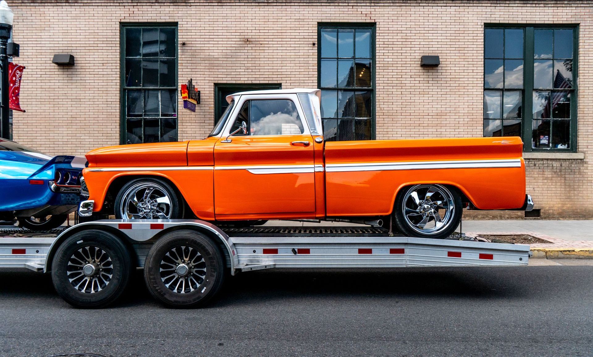 Classic orange pickup truck on trailer in front of brick building, Bristol, Tennessee.